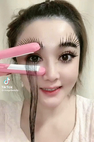 A Woman Is Holding A Pink Hair Straightener Over Her Eyebrows And The Hashtag Tiktok Is On The Bottom Right GIF
