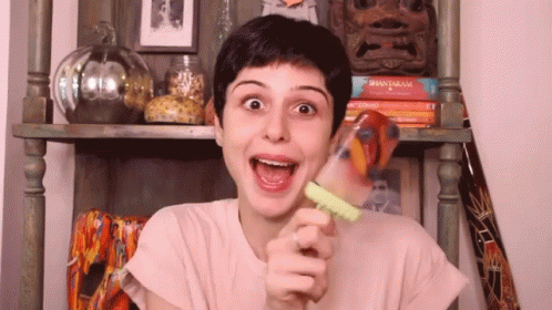 A Woman Is Holding A Popsicle In Her Hand And Making A Face . GIF