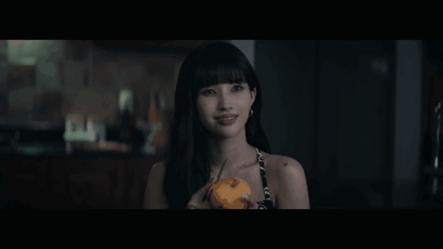 A Woman Is Holding A Pumpkin In Her Hand And Looking At The Camera GIF