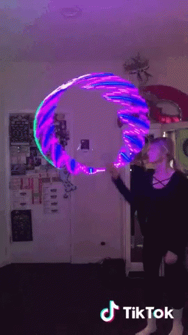 A Woman Is Holding A Purple And Blue Hula Hoop With Tiktok Written On The Bottom Right GIF