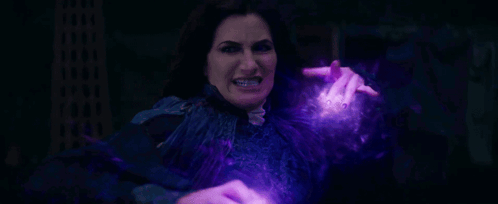 A Woman Is Holding A Purple Object In Her Hand And Making A Funny Face . GIF