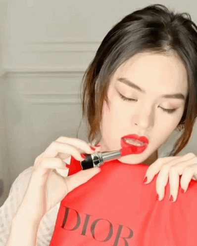 A Woman Is Holding A Red Dior Bag In Her Hand GIF