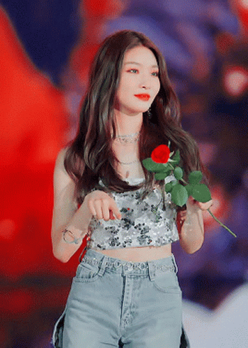A Woman Is Holding A Red Rose In Her Hand GIF