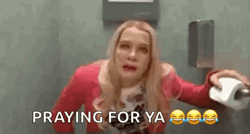 A Woman Is Holding A Roll Of Toilet Paper In A Bathroom And Praying For Ya . GIF