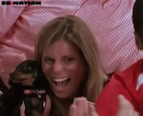 A Woman Is Holding A Small Dog And Laughing With A Sb Nation Logo In The Background GIF