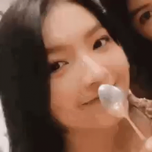 A Woman Is Holding A Spoon In Her Mouth While Another Woman Looks On . GIF