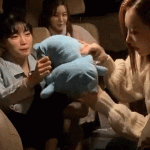 A Woman Is Holding A Stuffed Animal In Her Hands While Sitting In A Car . GIF