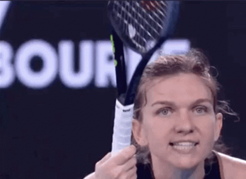 A Woman Is Holding A Tennis Racquet In Front Of A Court Sign GIF