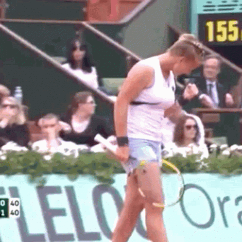 A Woman Is Holding A Tennis Racquet In Front Of A Sign That Says Lelo Ora GIF