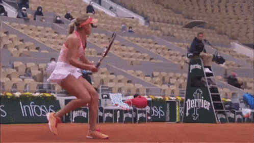 A Woman Is Holding A Tennis Racquet In Front Of An Emirates Fly Better Sign GIF