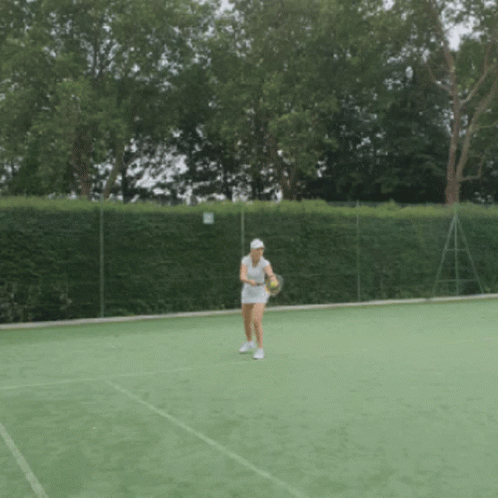A Woman Is Holding A Tennis Racquet On A Court GIF