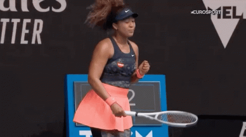 A Woman Is Holding A Tennis Racquet On A Tennis Court And Celebrating . GIF