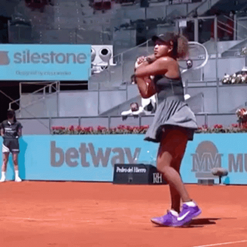 A Woman Is Holding A Tennis Racquet On A Tennis Court . GIF