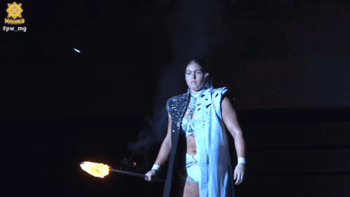A Woman Is Holding A Torch In Front Of A Sign That Says Fpw Mg GIF