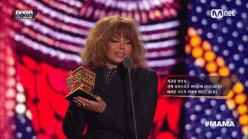A Woman Is Holding A Trophy And Speaking Into A Microphone At A Mama Event GIF