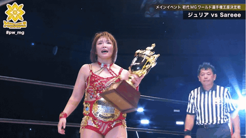 A Woman Is Holding A Trophy In Front Of A Referee And The Words #Jpw_mg Are Above Her GIF