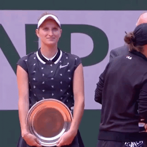 A Woman Is Holding A Trophy In Front Of A Sign That Says Np GIF
