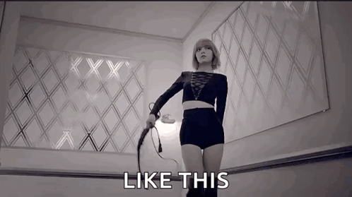 A Woman Is Holding A Whip In A Black And White Photo And The Words `` Like This '' Are Next To Her . GIF