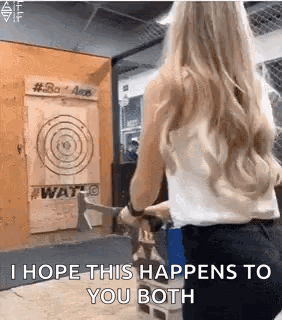 A Woman Is Holding An Axe In Front Of A Target And Says `` I Hope This Happens To You Both '' . GIF