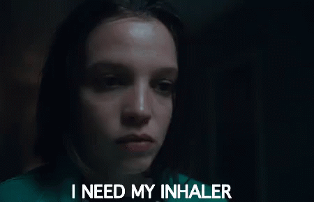 A Woman Is Holding An Inhaler In Her Hand In Front Of Her Face . GIF