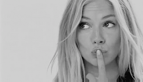 A Woman Is Holding Her Finger To Her Lips And Making A Shhh Gesture . GIF