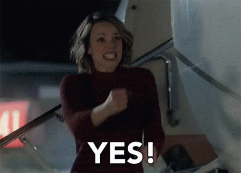 A Woman Is Holding Her Fist In The Air And Says Yes GIF
