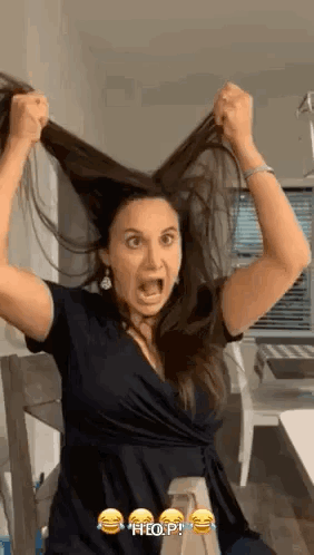 A Woman Is Holding Her Hair In The Air With Her Mouth Open . GIF
