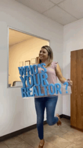 A Woman Is Holding Up A Sign That Says Who 'S Your Realtor GIF