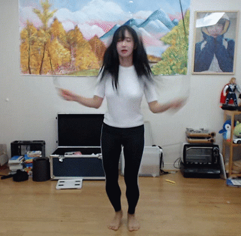 A Woman Is Jumping A Jump Rope In Front Of A Painting Of Mountains GIF