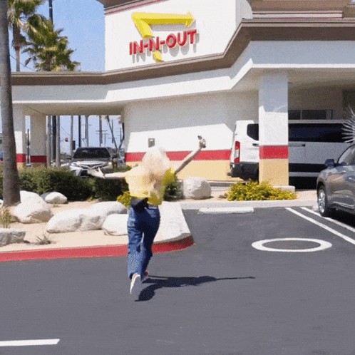 A Woman Is Jumping In Front Of An In N Out Restaurant GIF