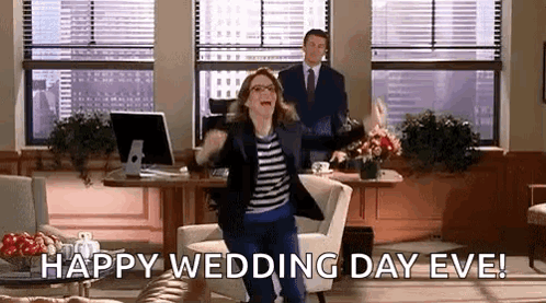 A Woman Is Jumping In The Air In An Office While A Man Stands Behind Her And Says Happy Wedding Day Eve . GIF