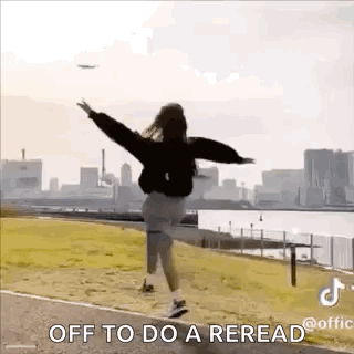 A Woman Is Jumping In The Air With Her Arms Outstretched In Front Of A City Skyline . GIF