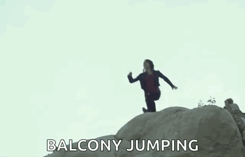 A Woman Is Jumping Off A Rock While A Man Watches . GIF