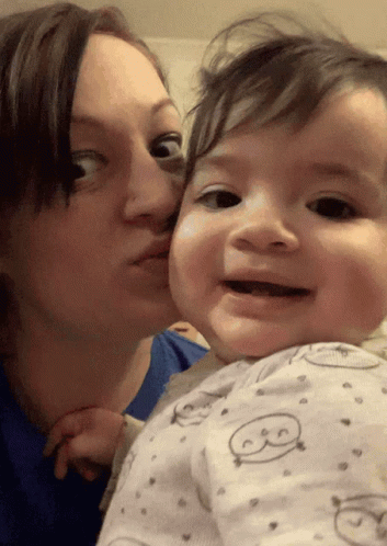 a woman is kissing a baby on the cheek who is wearing a pajama with the letter b on it
