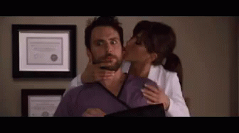 A Woman Is Kissing A Man On The Cheek While Holding His Neck . GIF