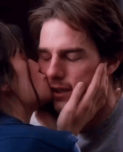 A Woman Is Kissing A Man On The Cheek With Her Hand . GIF