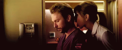 A Woman Is Kissing A Man On The Neck In A Room . GIF