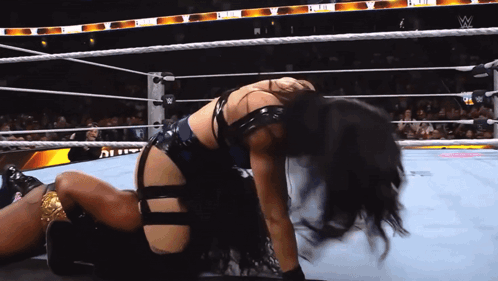 A Woman Is Kneeling Down In A Wrestling Ring With The W Logo On The Ropes GIF