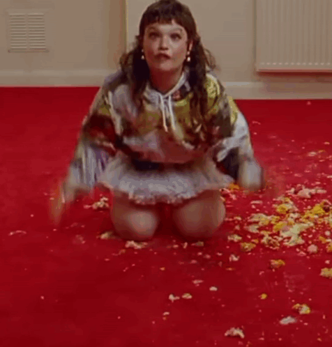 A Woman Is Kneeling On The Floor In A Room Covered In Flowers . GIF