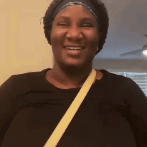 A Woman Is Laughing And Clapping Her Hands While Wearing Headphones . GIF