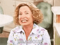 A Woman Is Laughing And Smiling While Sitting In A Chair . GIF