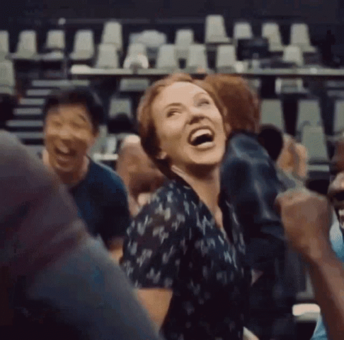 A Woman Is Laughing In A Crowd Of People In A Theater . GIF