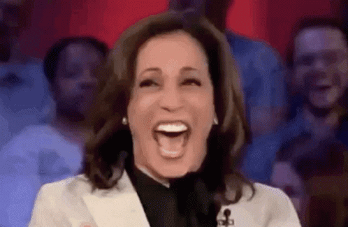 A Woman Is Laughing In Front Of A Crowd Of People . GIF