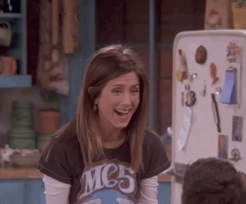 A Woman Is Laughing In Front Of A Refrigerator . GIF