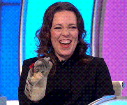 A Woman Is Laughing While Holding A Cat In Her Hand On A Television Show . GIF