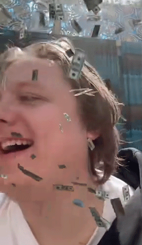 A Woman Is Laughing While Money Falls On Her Face GIF