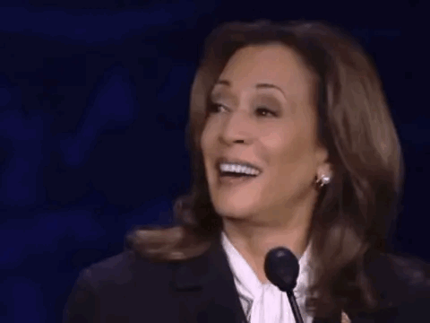 A Woman Is Laughing While Speaking Into A Microphone On A Stage . GIF