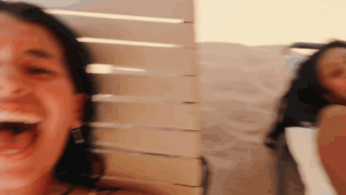 A Woman Is Laughing With Her Mouth Open And Another Woman Is Behind Her GIF