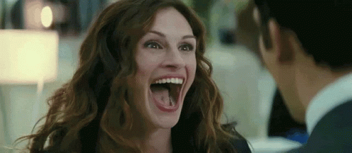 A Woman Is Laughing With Her Mouth Open And Sticking Out Her Tongue . GIF