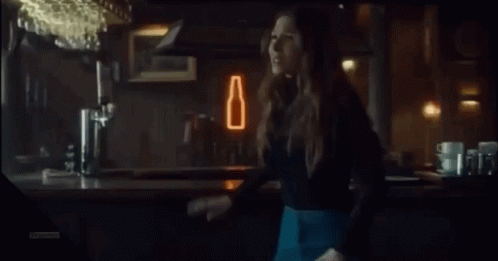 A Woman Is Laughing With Her Mouth Open In A Bar GIF